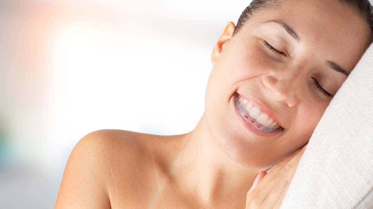 woman sleeping and wearing bite plate in the mouth to save teeth from grinding caused by bruxism.