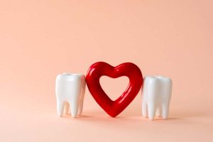 Two teeth and red heart on a pastel background. Oral care and St. Valentine's day concept.