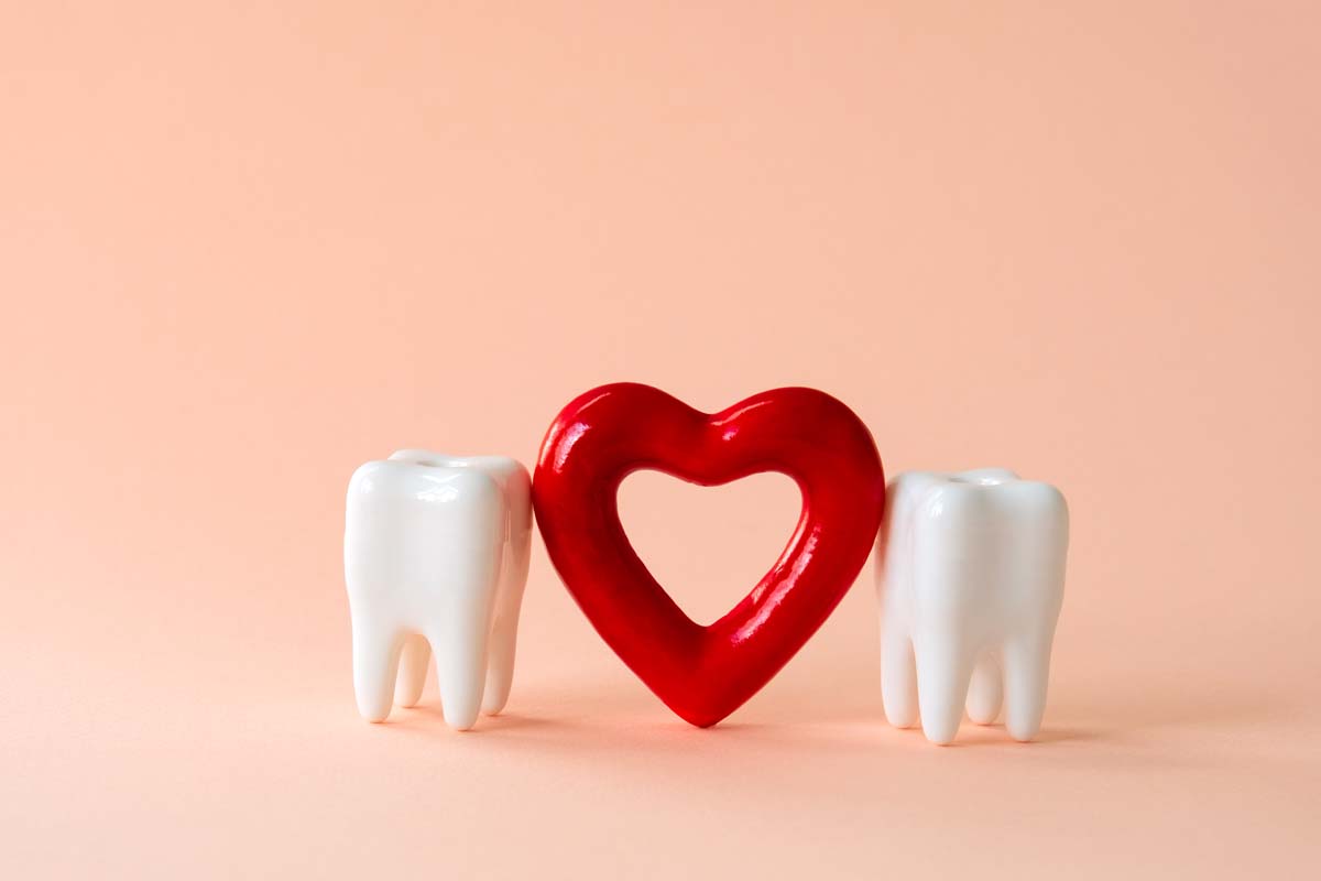 Two teeth and red heart on a pastel background. Oral care and St. Valentine's day concept.