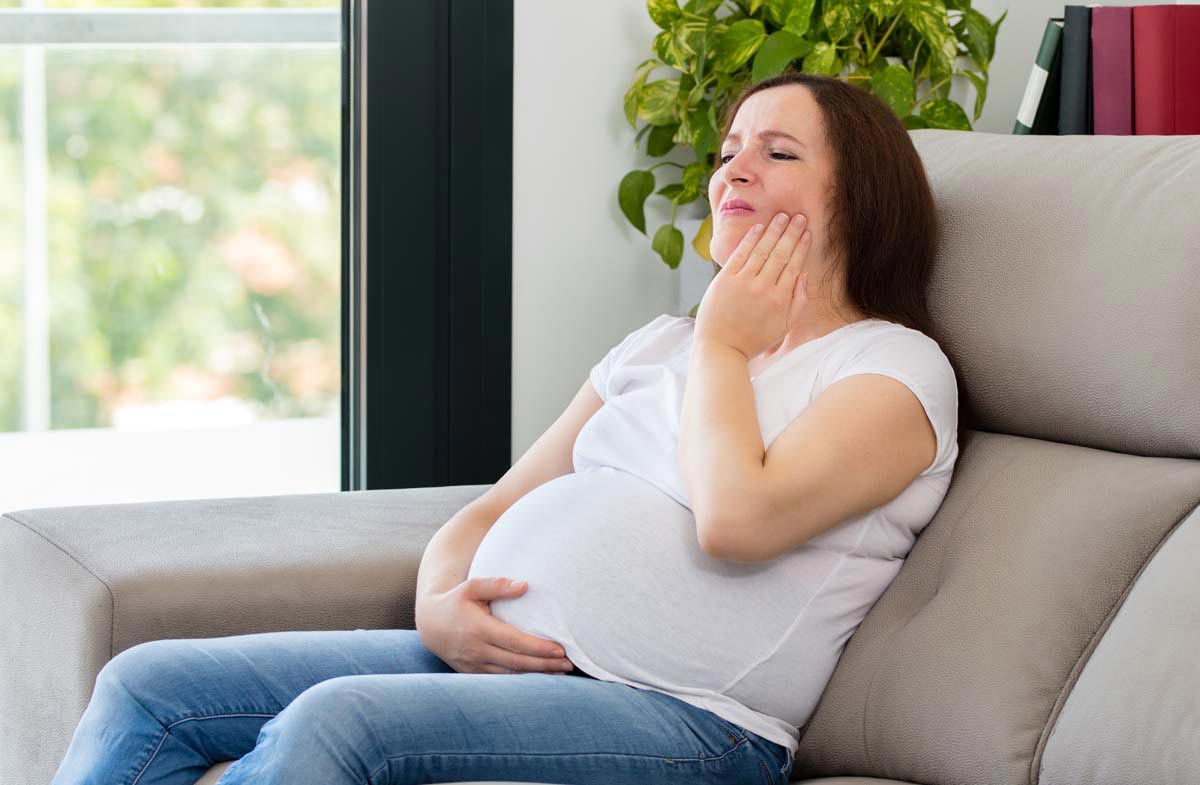 Pregnant Woman Suffering Toothache with Hand on Face at Home in Frenchs Forest
